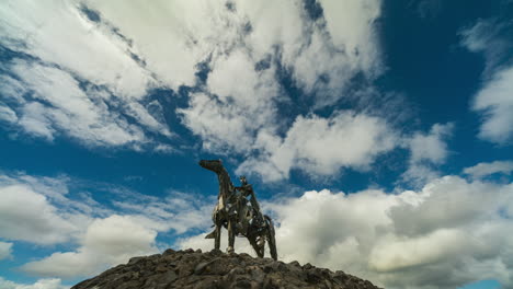 time lapse of the gaelic chieftain modern art metal statue on sunny day with moving clouds in the sky in county roscommon, ireland