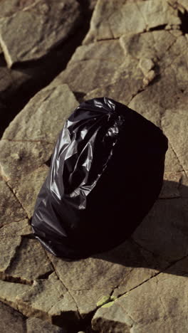 a black garbage bag lying on a rocky ground