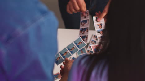 close up of a group of friends having fun looking at prints from photo booth with props 15