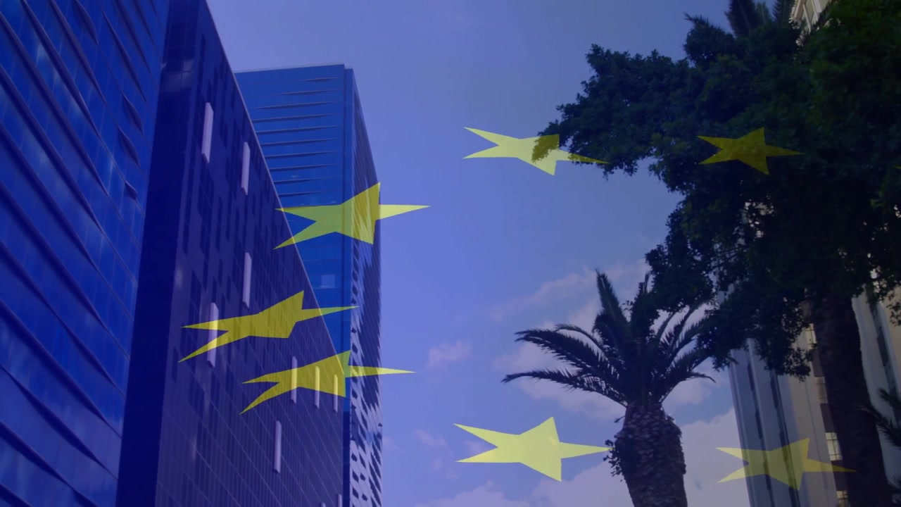 Stelle gialle semitrasparenti che fluttuano da sinistra a destra attraverso un canyon urbano, visualizzando un motivo dell'UE.