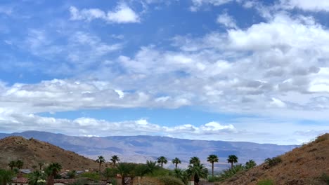 4K-Zeitraffer-Eines-Wüstenberges-Mit-Wolken-Und-Palmen-Mit-Blauem-Himmel