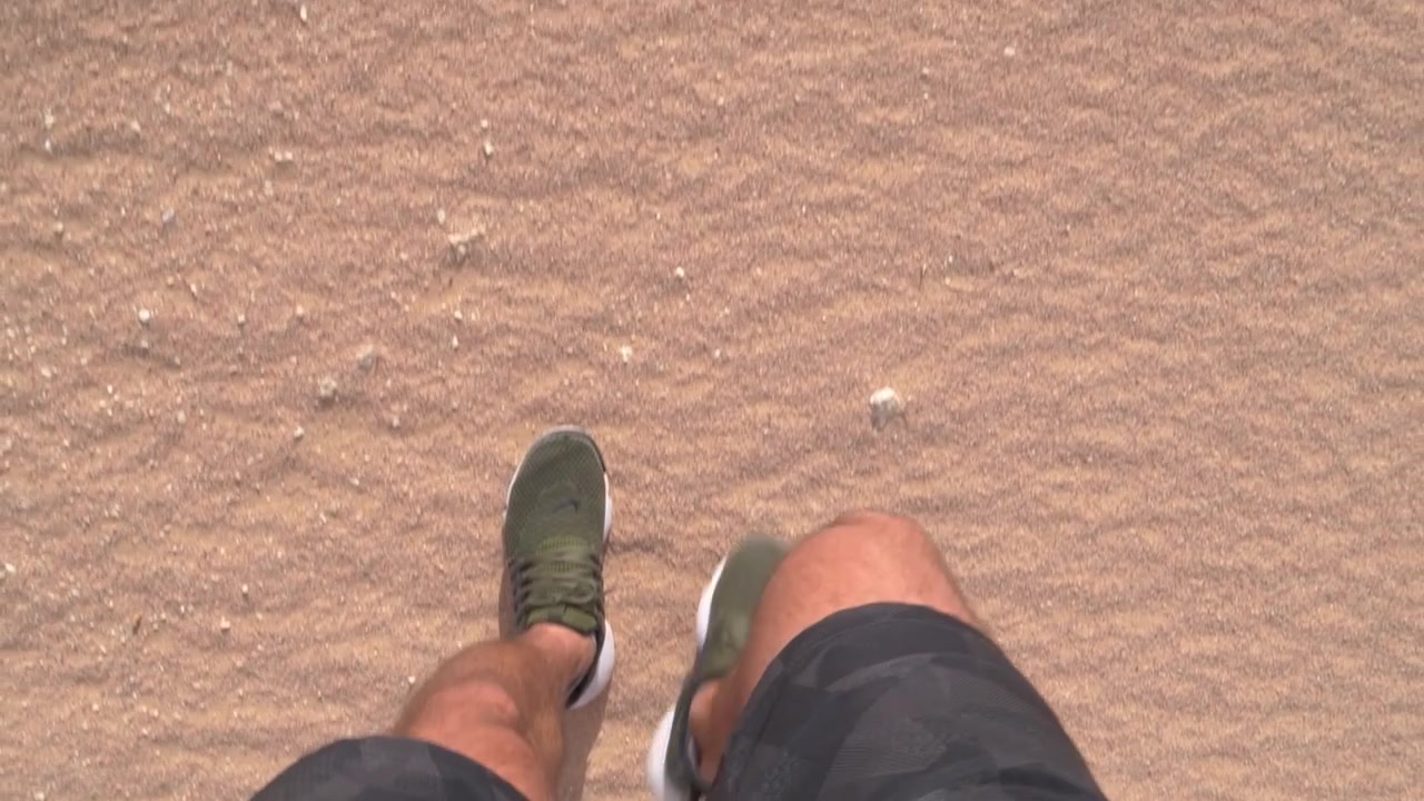 Uomo che cammina attraverso sabbia dorata POV