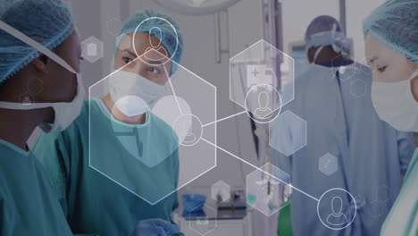 animation of medical icons and data over diverse female surgeons talking during operation