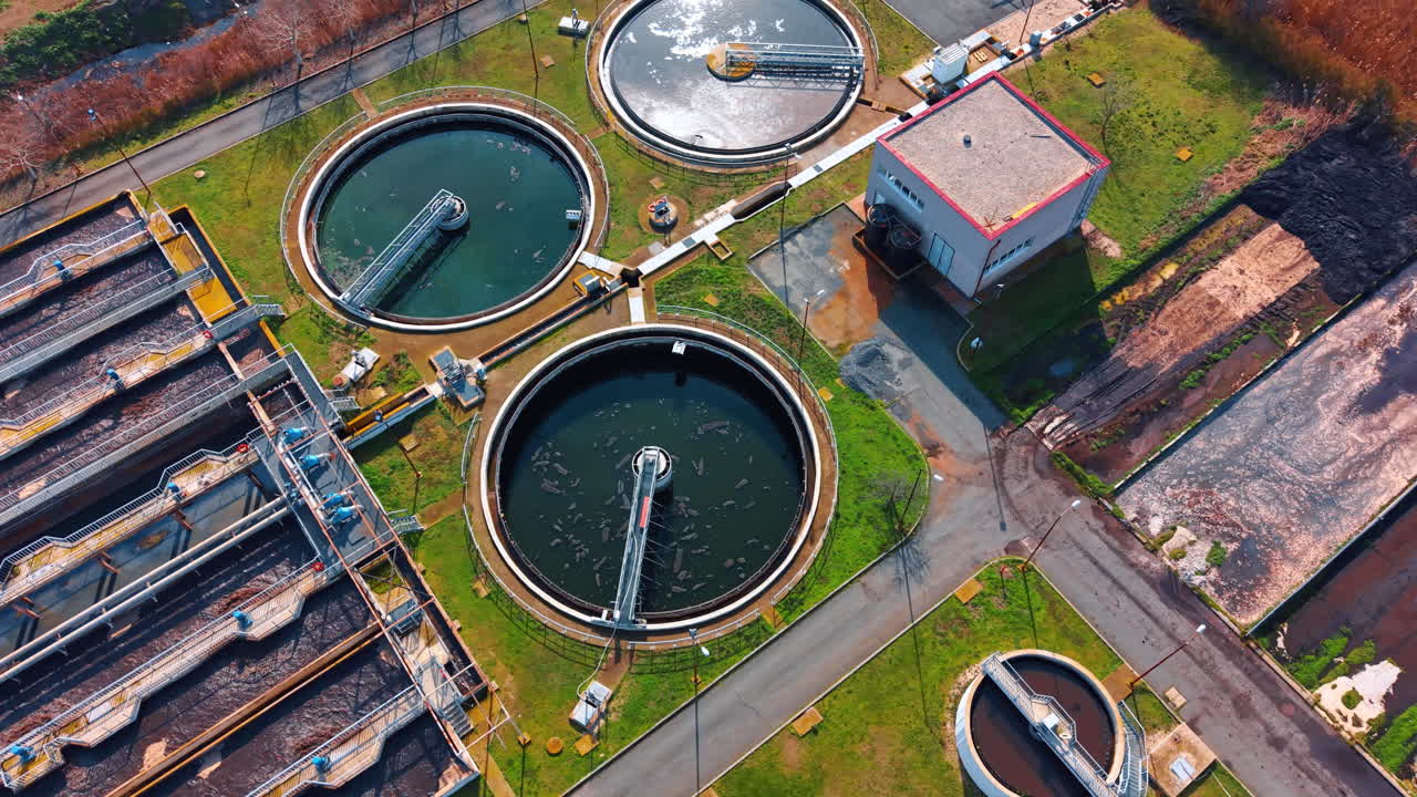 Top view of sewage treatment plant layout with buildings. Vertical aerial shot showing various stages of water treatment including circular tanks, aeration basins and utility buildings