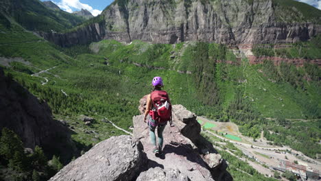 vista posterior de la mujer en la cima del acantilado sobre el abismo y el impresionante paisaje del valle cerca de telluride, colorado, ee.uu.