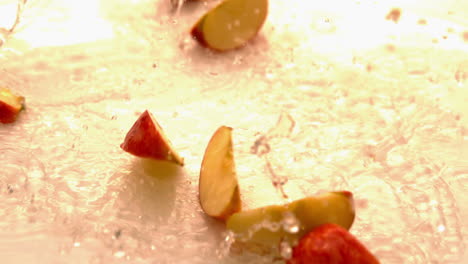 apple pieces falling and bouncing on white wet surface