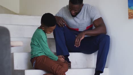 African american father and son sitting on the stairs talking and smiling