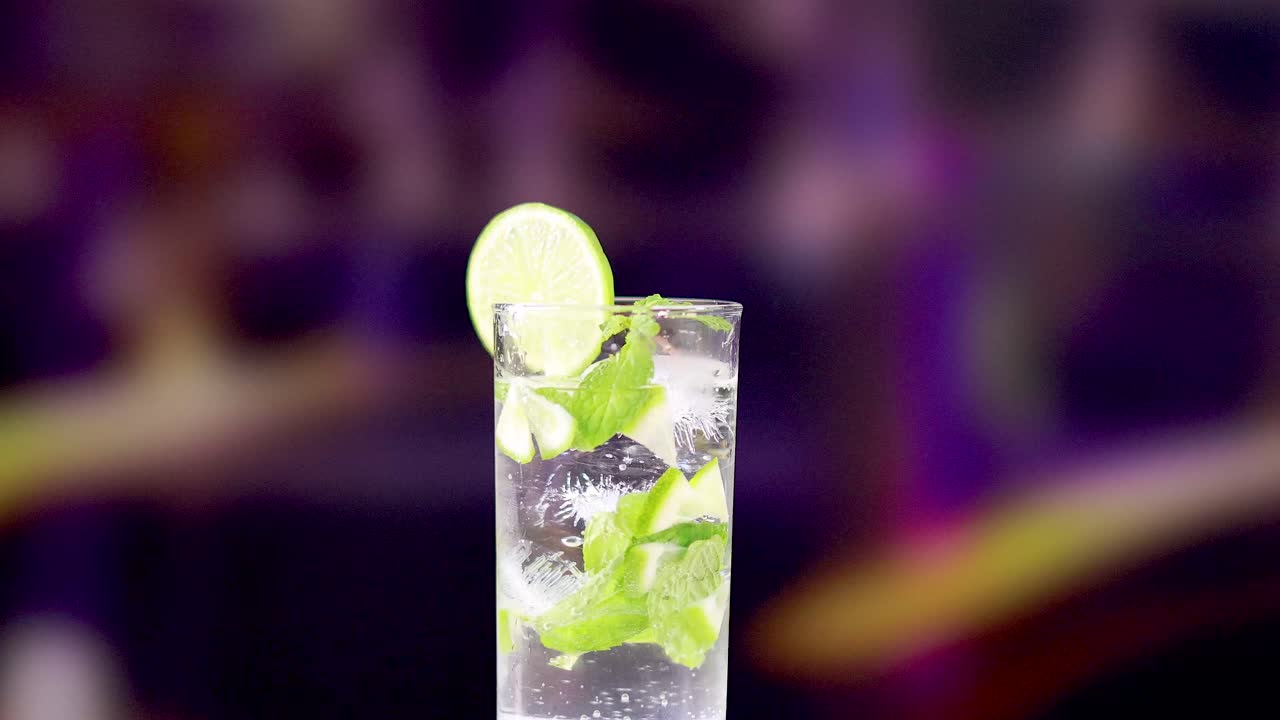 A vibrant mojito cocktail with lime and mint, set against a colorful blurred background, highlighting its refreshing appeal