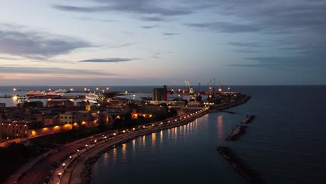 cinematic drone shot during sunset in italian shore, city lights and sea.