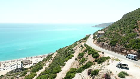 Albania,-Vista-Aérea-Desde-Un-Dron-De-Coches-Conduciendo-Por-Una-Hermosa-Carretera-A-Lo-Largo-De-Una-Empinada-Ladera-De-Montaña-Con-Vistas-Al-Mar