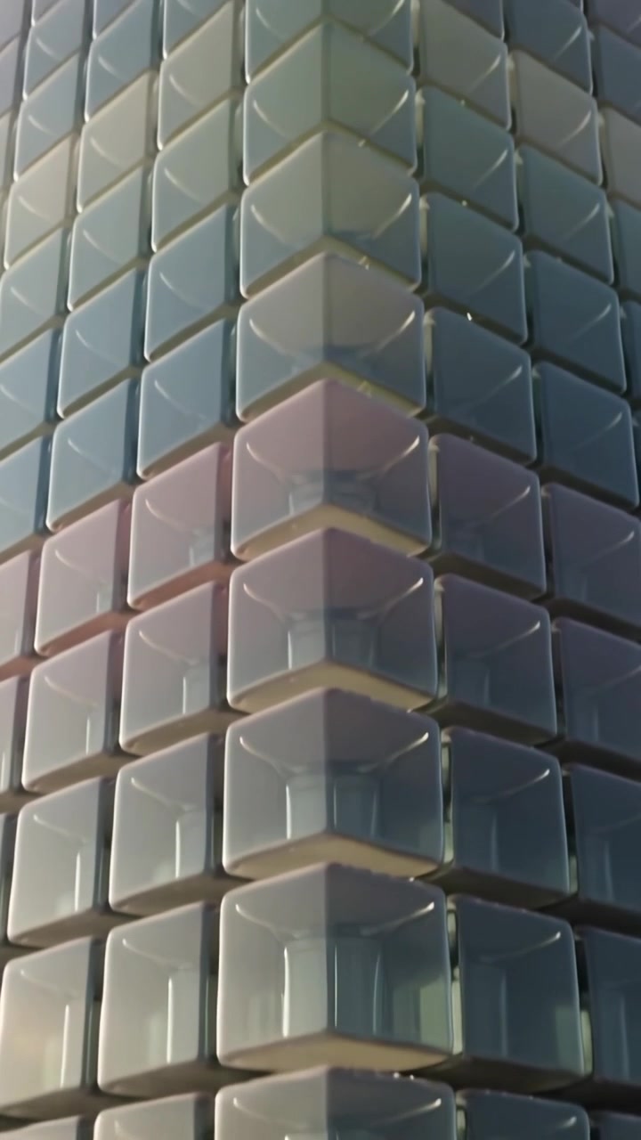 Video vertical: Cámara inclinándose y retrocediendo, revelando módulos de vidrio apilados y la altura completa de la torre.