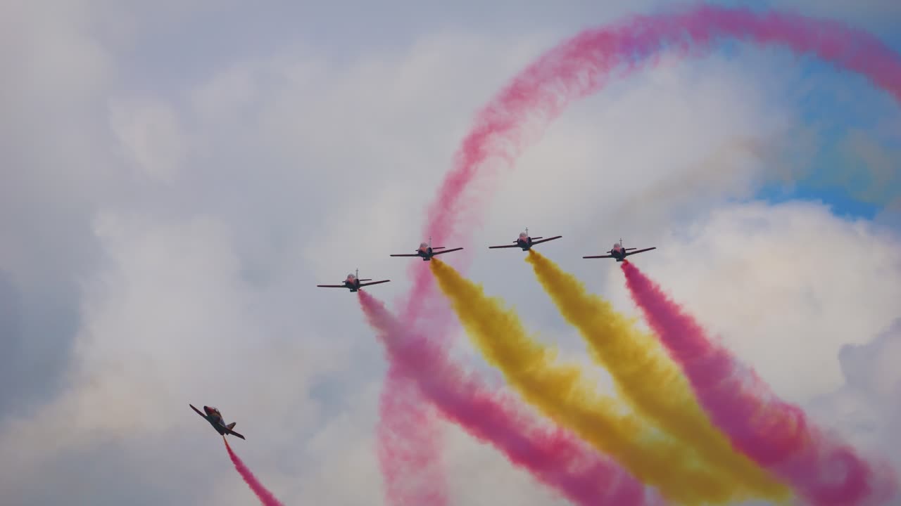 The Patrulla Águila is the aerobatic team of the Spanish Air Force. They fly a stunt and release the Spanish colors in the form of smoke from the planes