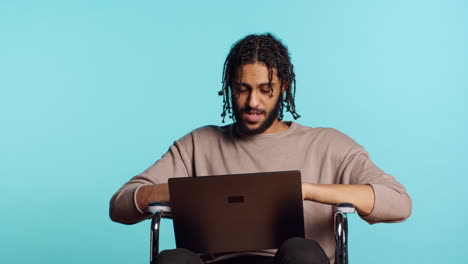 Man in wheelchair chatting with friend over internet videocall using laptop