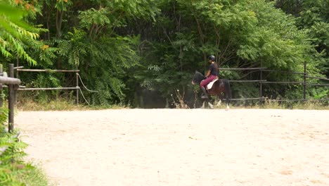 Distant rear view of a helmeted woman riding a pony away from the track after a training session