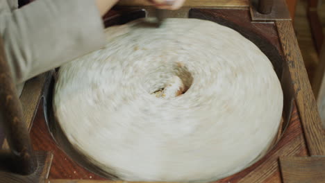 The-baker-grinds-grain-into-flour.-Antique-hand-mill-in-operation-with-an-authentic-200-year-old-millstone