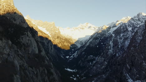 Toma-Panorámica-Aérea-Desde-El-Paisaje-Cubierto-De-Nieve-Hasta-El-Bosque-Del-Valle-Val-Di-Mello