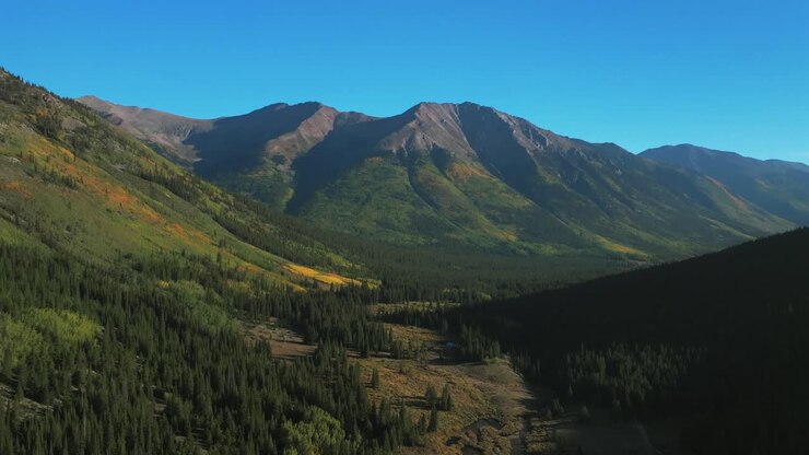 Vista aerea con drone di Huron Peak e Collegiate Peaks, dal punto di partenza del sentiero nella valle mattutina, tra La Plata e Buena Vista, Colorado, Montagne Rocciose. Scena estiva/autunnale con campeggio, pioppi tremuli dai colori vivaci, cielo blu soleggiato, ripresa con movimento circolare a destra.
