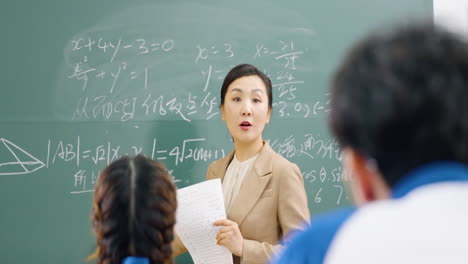 asian school elementary classroom of children listening attentively to teacher giving lecture to students