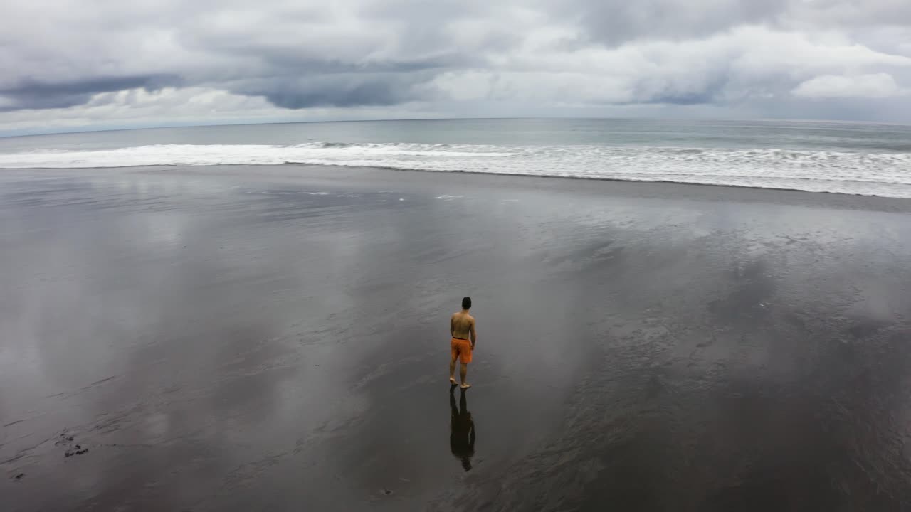 antena de un joven haciendo una voltereta hacia atrás en una playa vacía, colombia