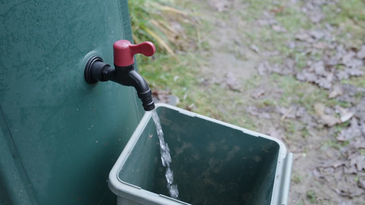 Rainwater reservoir, open tap to collect water. Ecological gesture to save water.