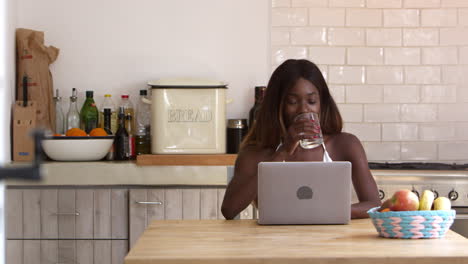 Mujer-Joven-Sonriente-Usando-Una-Computadora-Portátil-En-Su-Cocina,-Filmada-En-R3d