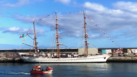 Fishing-Boat-Sailing-In-The-Ocean-With-NRP-Sagres-Tall-Ship-And-School-Ship-At-Funchal-Port-In-Madeira-Island,-Portugal