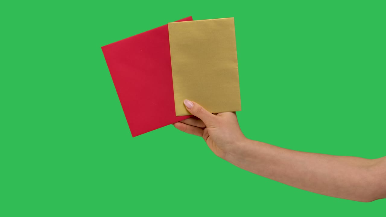 여성 손은 두 개의 종이 봉투를 들고, 녹색 화면 배경에서 격리 된 클로즈업, 스튜디오에서 크로마 키, 빨간색과 노란색 빈 봉투, 편지, 축하, 발렌타인, 느린 동작.
