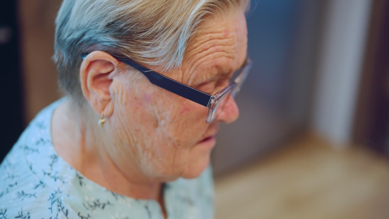 Anziana signora in cucina. Nonna con occhiali che si gode il suo tempo. Nonna bianca riflessa in una calda scena di cucina. Primo piano di un'anziana donna con occhiali in piedi in una cucina accogliente.