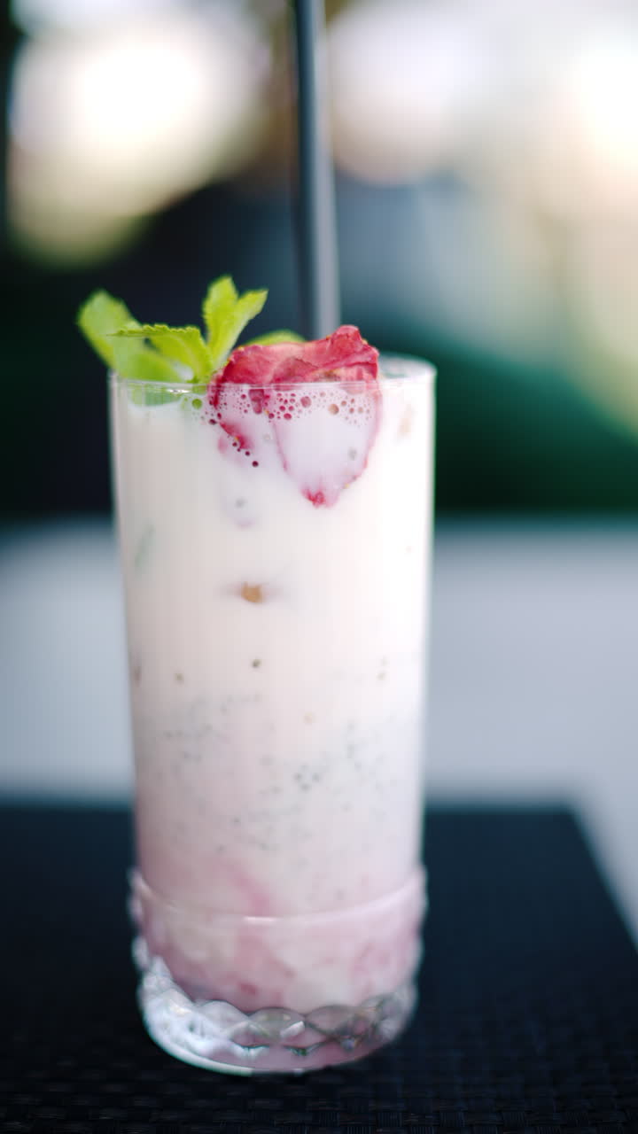 Una bevanda alla fragola con una cannuccia nera su un tavolo in un ristorante. Verticale