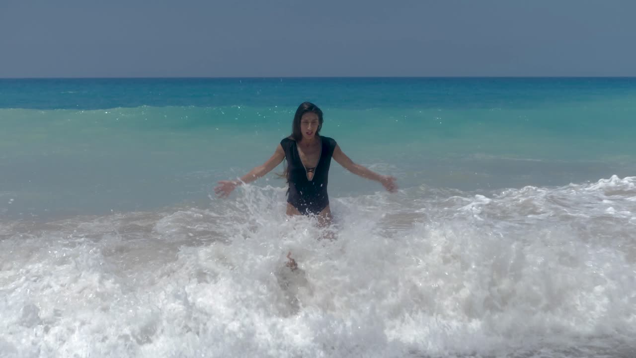 Petite Female in Swimsuit Enjoying on Rough Mediterranean Sea Waves Breaking on Beach, Full Frame