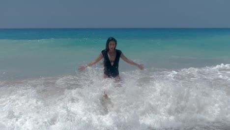 petite female in swimsuit enjoying on rough mediterranean sea waves breaking on beach, full frame