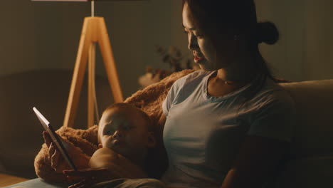 mother and child reading on a tablet at night