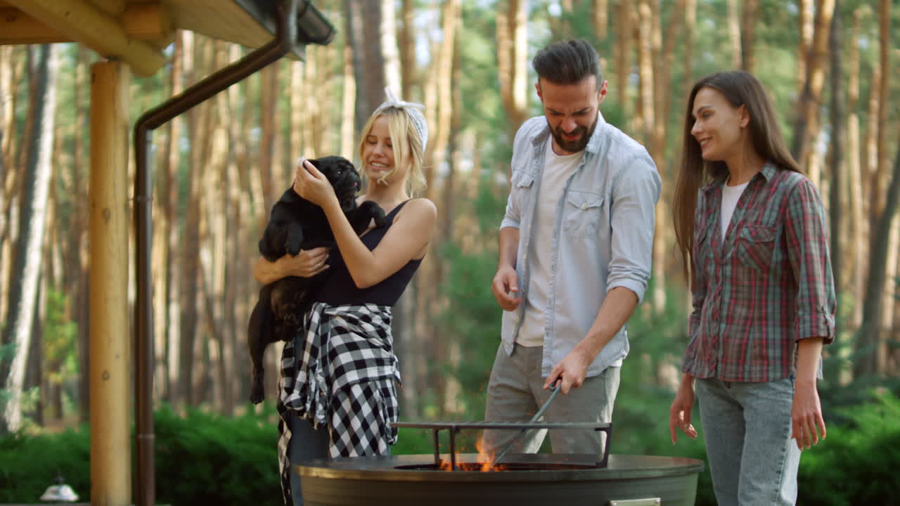 Uomo sorridente che prepara la griglia del barbecue per cucinare in giardino. Amici che si godono la festa.