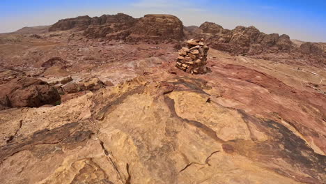 climbing a bare rock to the top with a pile of stones. deserted landscape with canyons in jordan, west asia.