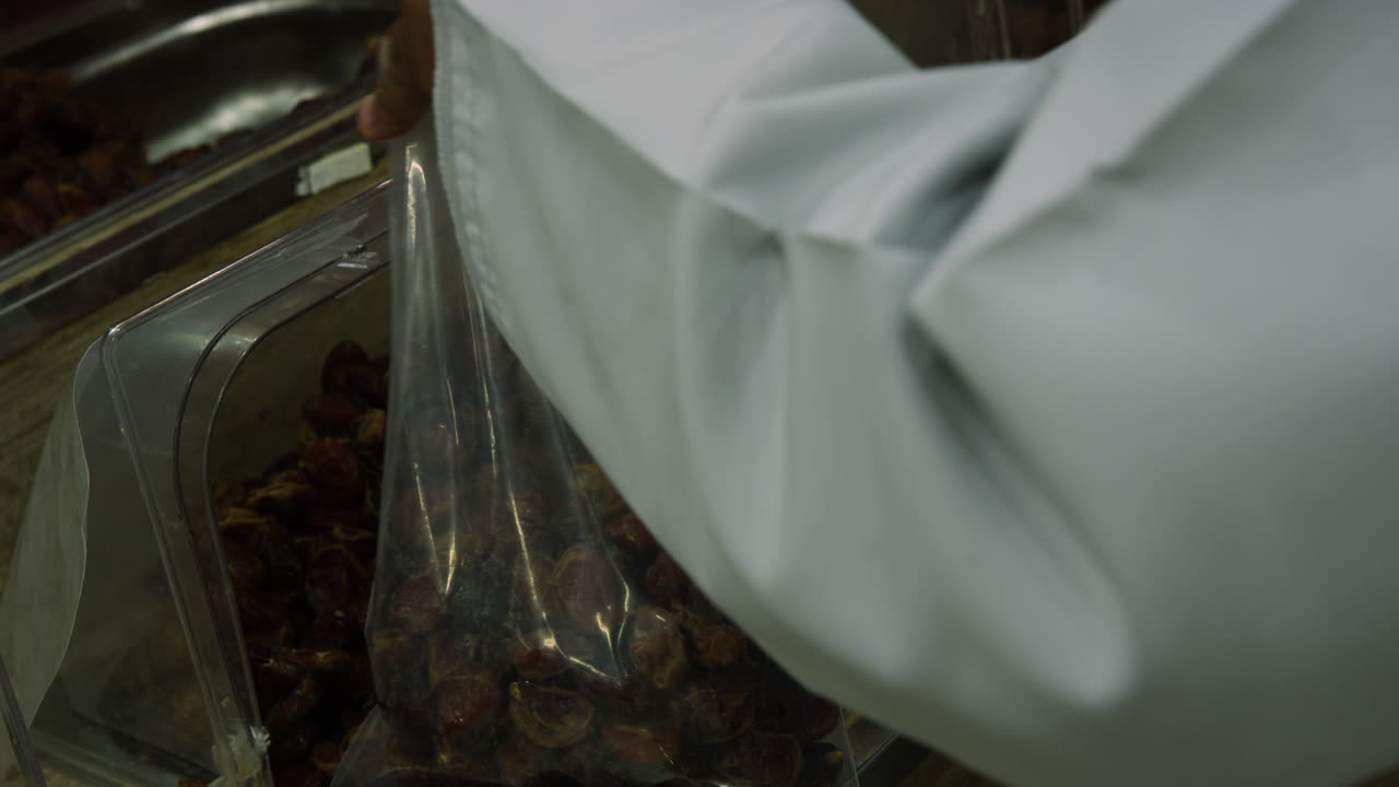 Hands filling bag with dates at Nizwa Souq marketplace, Oman, close up