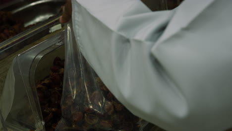hands filling bag with dates at nizwa souq marketplace, oman, close up
