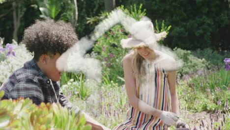 Animación-De-La-Casa-De-Las-Nubes-Sobre-Una-Pareja-Feliz-Y-Diversa-Plantando-Flores-En-Un-Jardín-Soleado