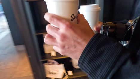 persona recibe y sostiene una taza de café para llevar