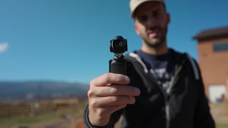 male freelancer holding 3-axis stabilized 4k handheld camera and moving around with hand