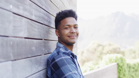portrait of happy african american man standing on sunny balcony smiling, copy space, slow motion