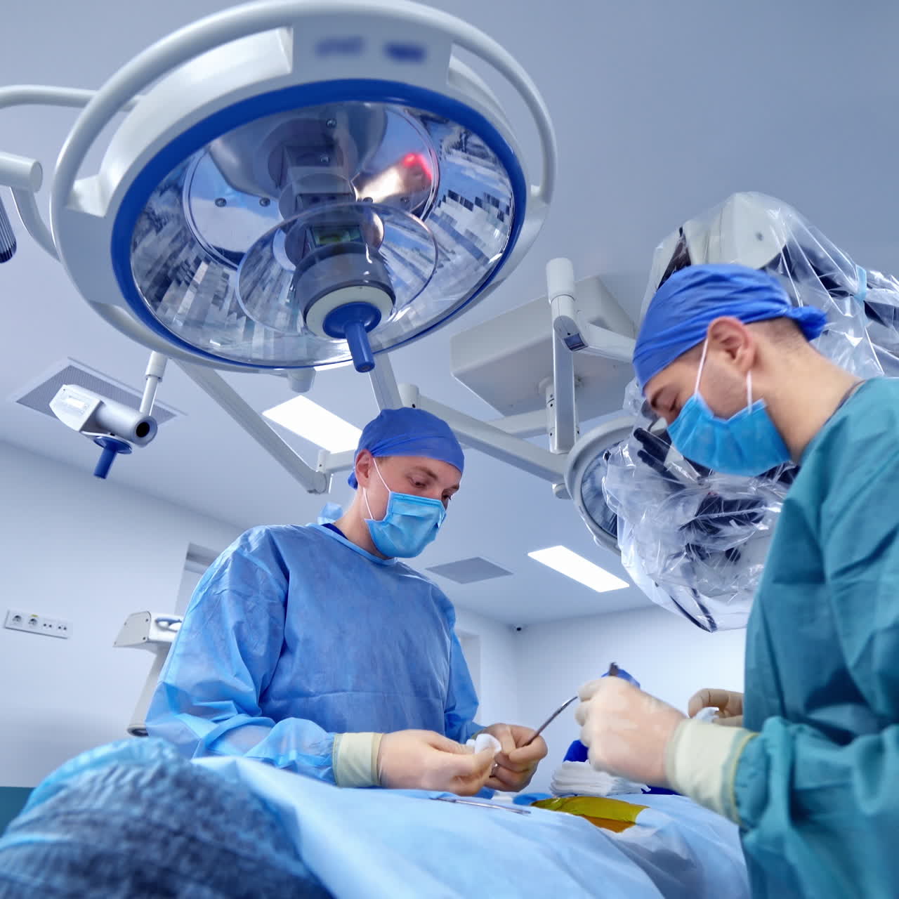Team of specialists performing operation in modern clinic. Surgeons in medical uniform with masks doing spinal surgery on a patient in private clinic.
