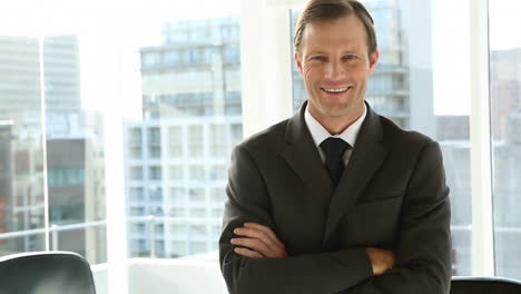 smiling businessman standing by window