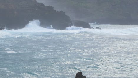 grandes olas del océano atlántico rompen en una costa rocosa en un día soleado durante una tormenta en puerto de la cruz en las canarias , plano medio ancho