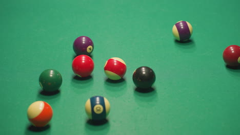 scattered billiard balls on green pool table after break shot, rolling in different directions. vibrant colors contrast with green felt, highlighting energy and motion in dynamic game scene