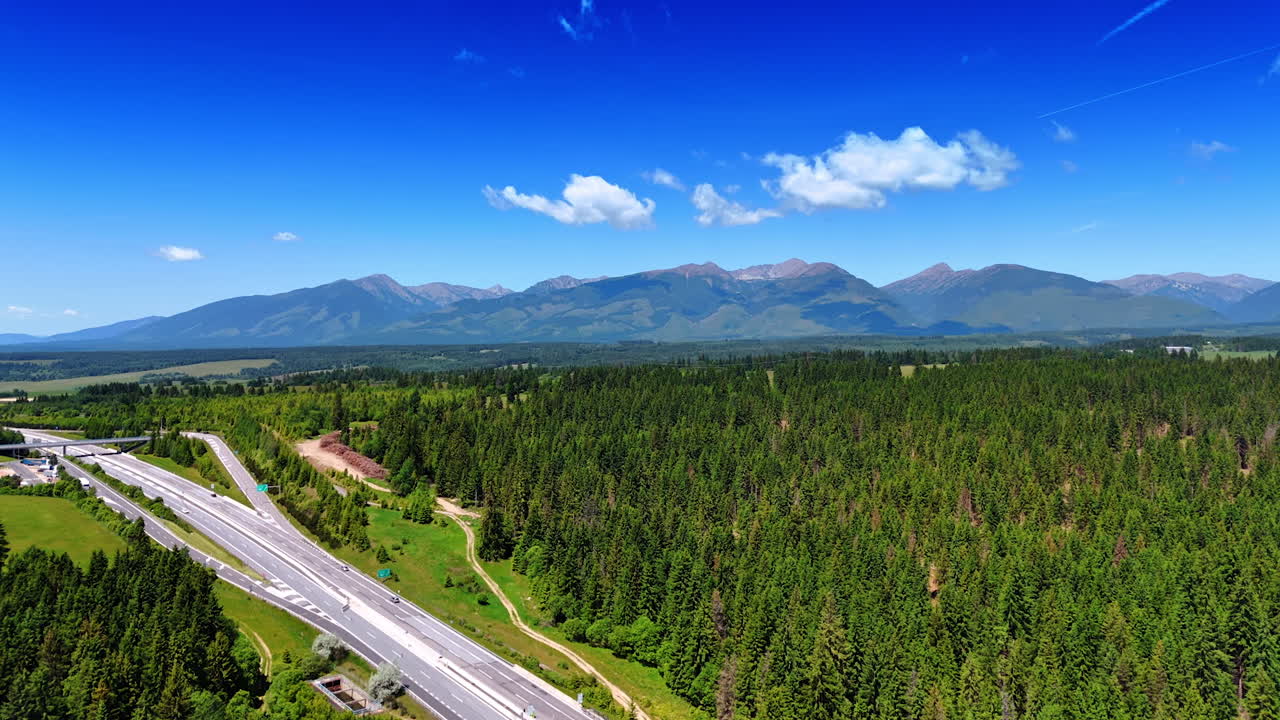 Multi-lane road in the countryside of Slovakia. Pine tree woods cover the valley surrounded by the Tatra mountains. Aerial view