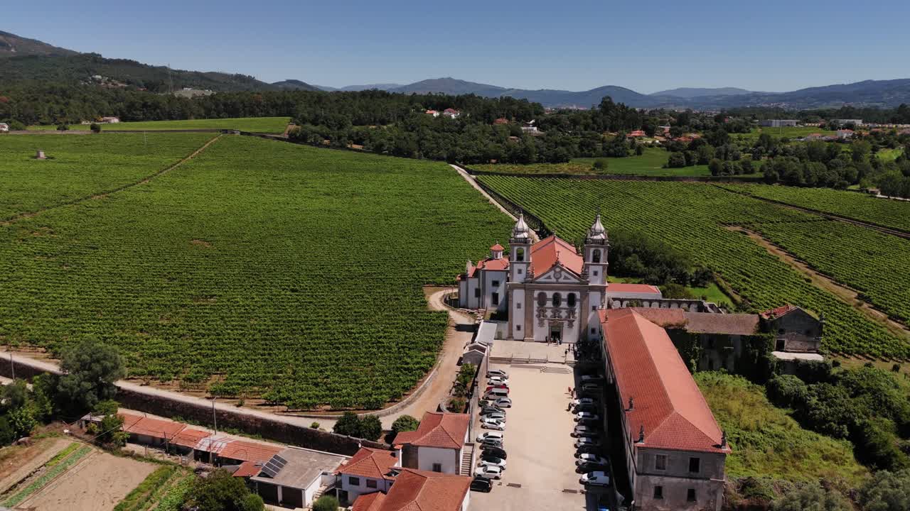 Mosteiro de Santo André de Rendufe surrounded by lush vineyards and mountainous landscape under a clear blue sky - drone