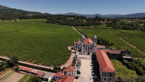 mosteiro de santo andré de rendufe surrounded by lush vineyards and mountainous landscape under a clear blue sky - drone