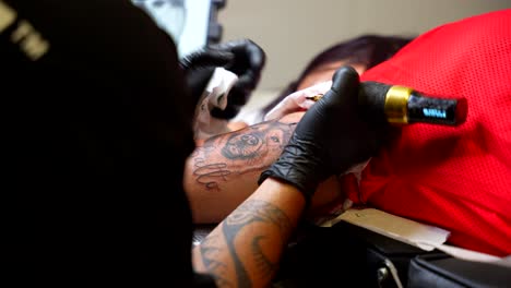tattoo artist carefully outlining design on client's arm, maintaining focus and precision