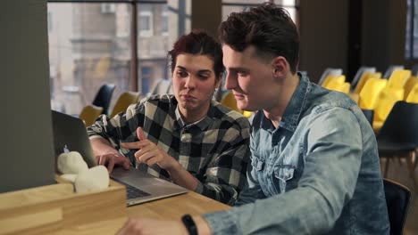 Couple-of-two-young-attractive-people-sitting-in-front-of-laptop-talking-about,-discussing-something.