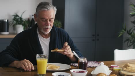 senior caucasian man eating breakfast at home.